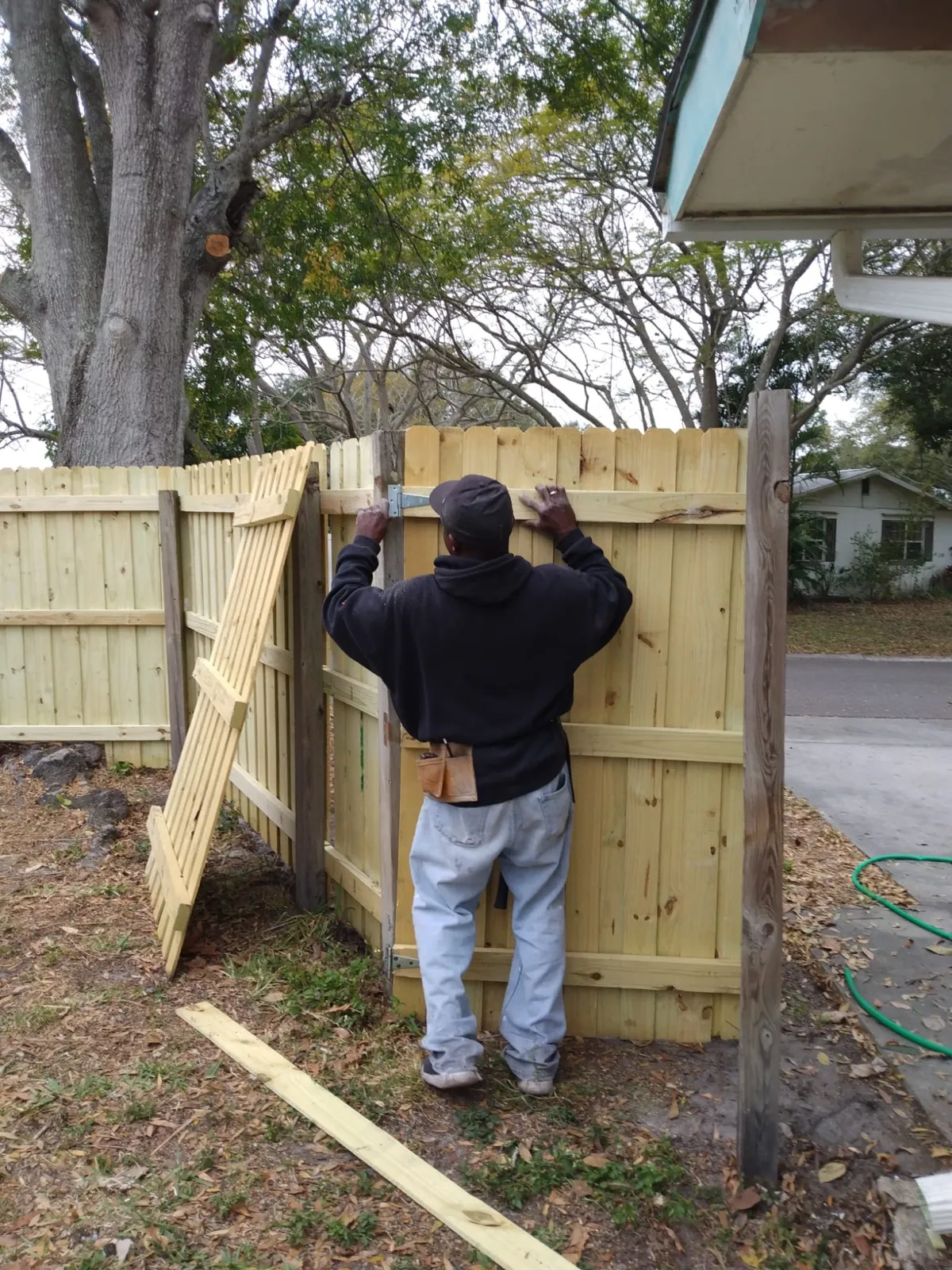 Jose fitting boards to a wood fence panel during an installation.