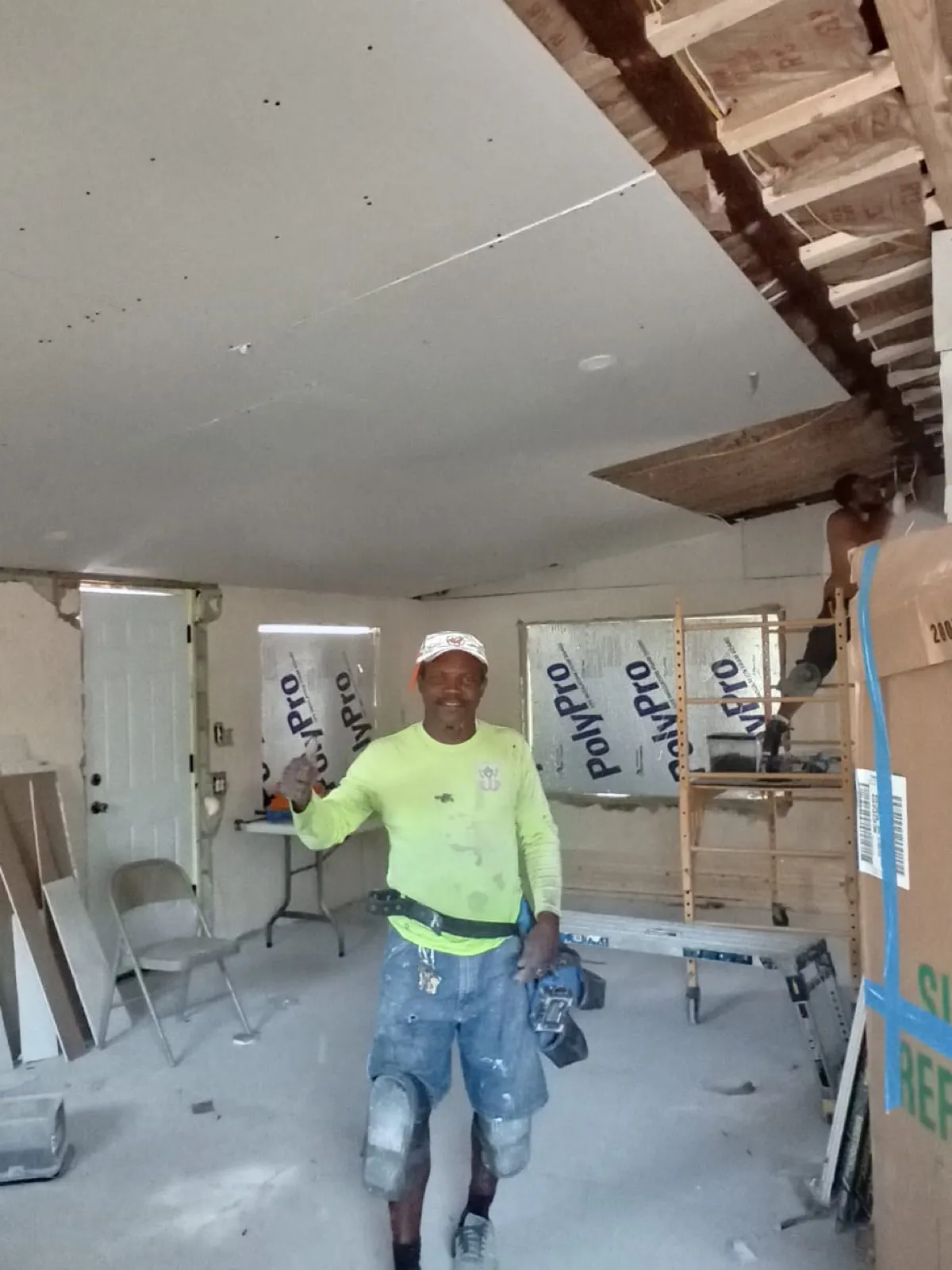 Jose in a room mid-renovation, with drywall going up on the ceiling.